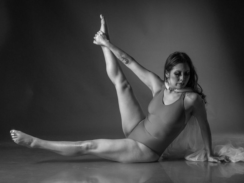 Woman performing a controlled yoga movement in a calm, minimalist studio.